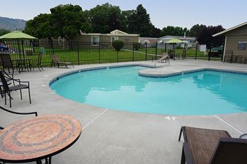 a resort style pool with chairs and tables and a fence around it at Park View Apartments, Wenatchee, 98801